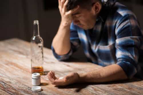 depressed man abusing pills and alcohol
