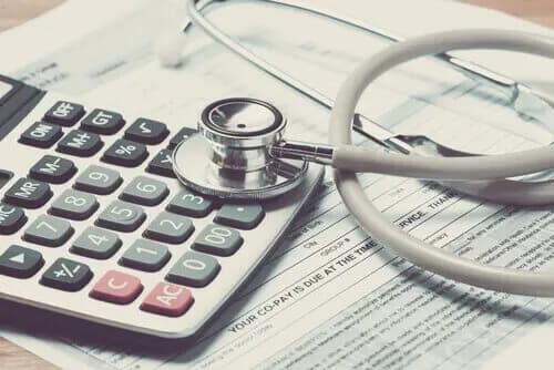 Calculator and stethoscope on top of insurance papers