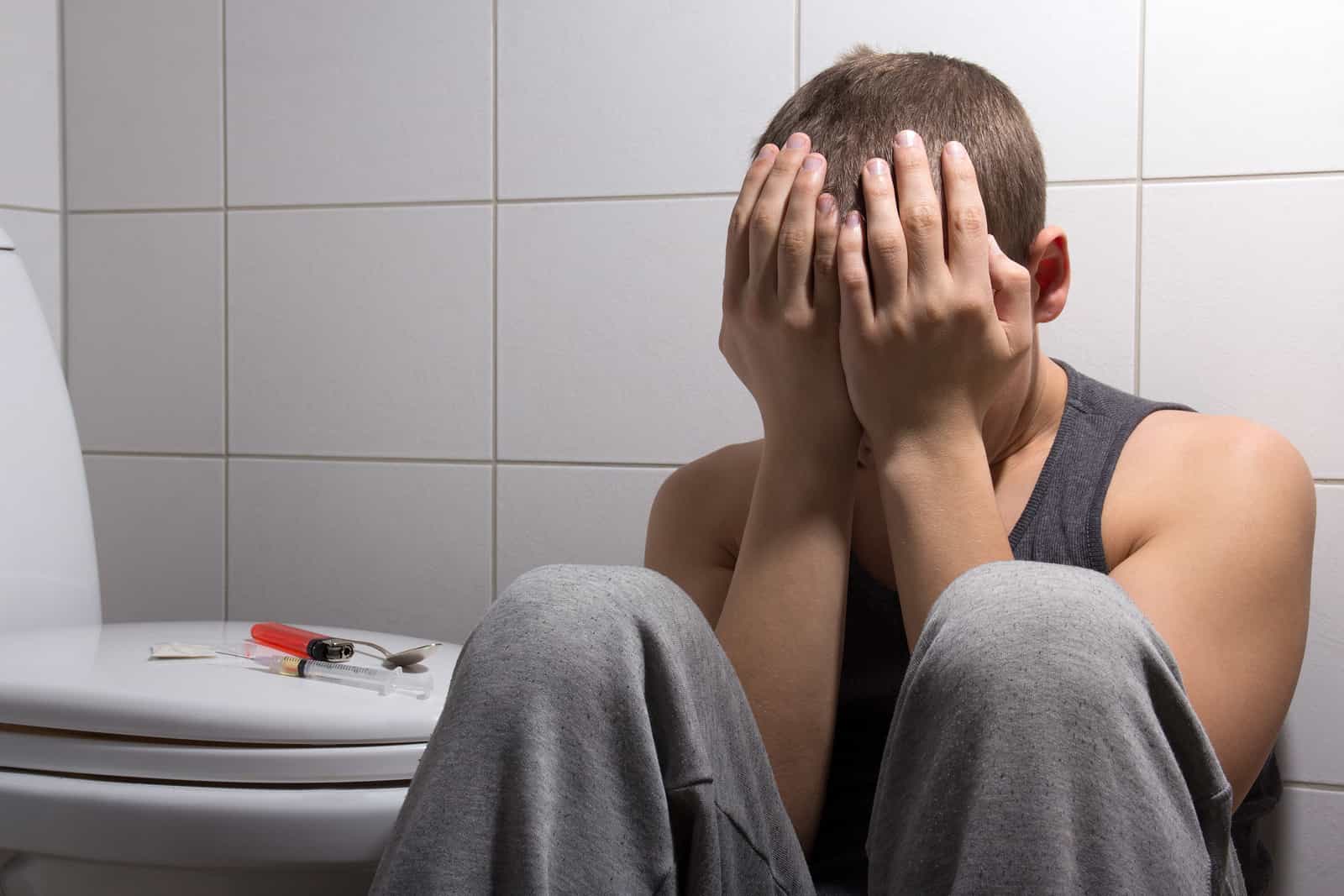 Stoned Man With Heroin Addiction Sitting In Bathroom